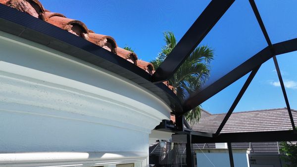 Close-up of aluminum frame connection to tile roof for a screen enclosure in Naples, FL, showcasing expert installation detail.